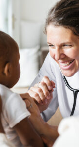 A doctor happily checks an infant's heartbeat with a stethoscope.
