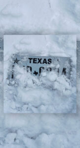 A Texas license plate covered in snow.